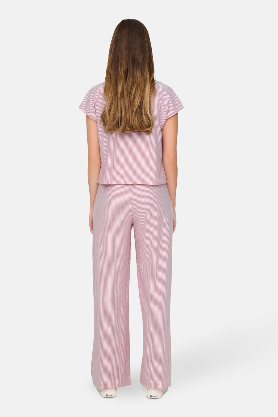Chemisier rose rayé de JDY, présenté de dos, porté avec un pantalon assorti et des chaussures blanches.
