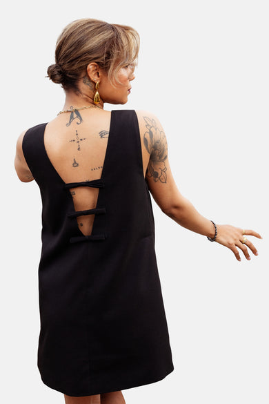 Robe noire ONLY® avec dos échancré orné de nœuds décoratifs, accessoirisée de bijoux dorés.
