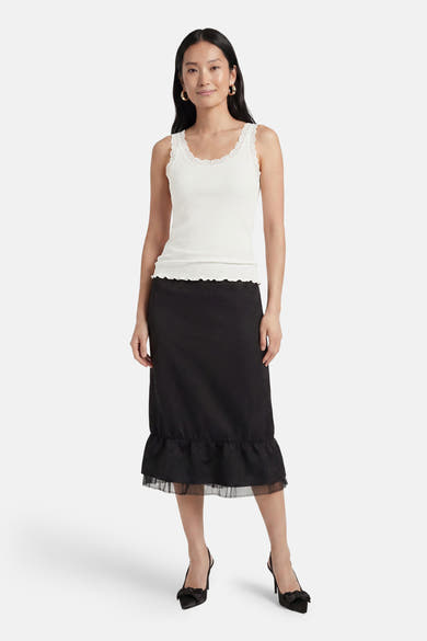 Top blanc côtelé sans manches de ONLY® à bordure dentelle et ourlet festonné, avec jupe noire et talons.