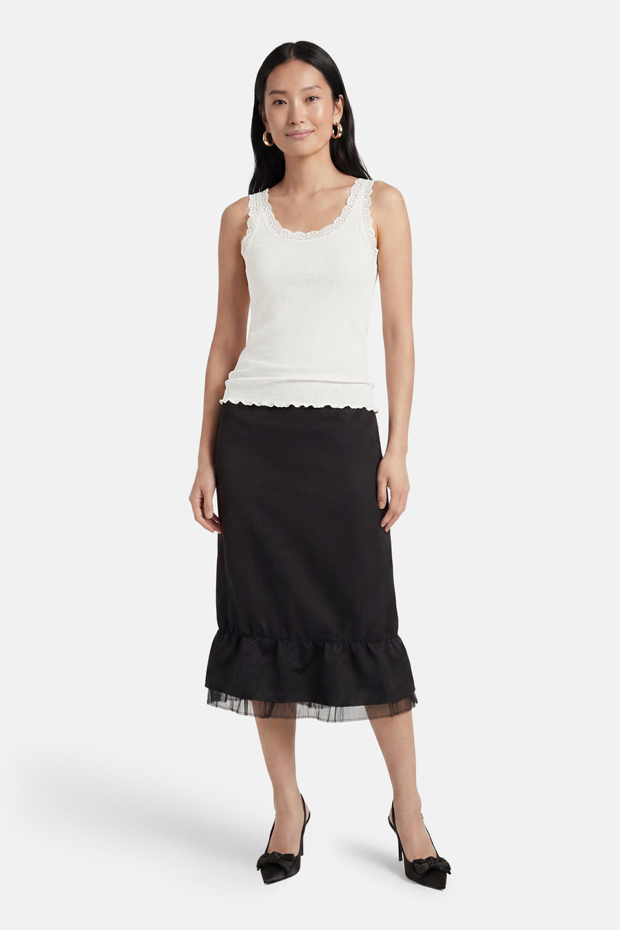 Top blanc côtelé sans manches de ONLY® à bordure dentelle et ourlet festonné, avec jupe noire et talons.