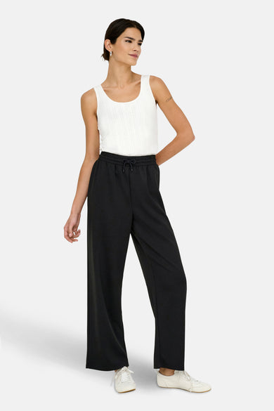 Zwarte joggingbroek van ONLY, gedragen met een witte tanktop en witte sportschoenen.