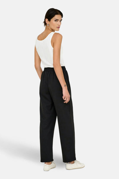 Zwarte joggingbroek van ONLY, met elastische tailleband en zakken, gedragen met een witte tanktop en crèmekleurige sneakers.