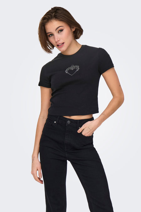 Zwart T-shirt met korte mouwen van ONLY®, versierd met een glinsterend hartmotief, gedragen met een zwarte jeans en platte schoenen.
