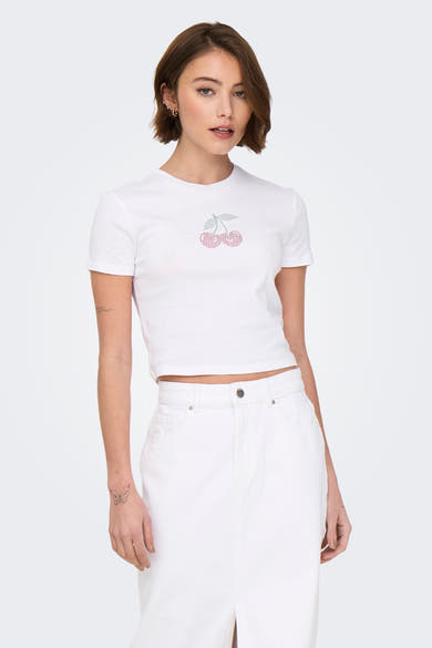 T-shirt blanc à manches courtes de ONLY, orné de cerises décoratives, porté avec un pantalon blanc.
