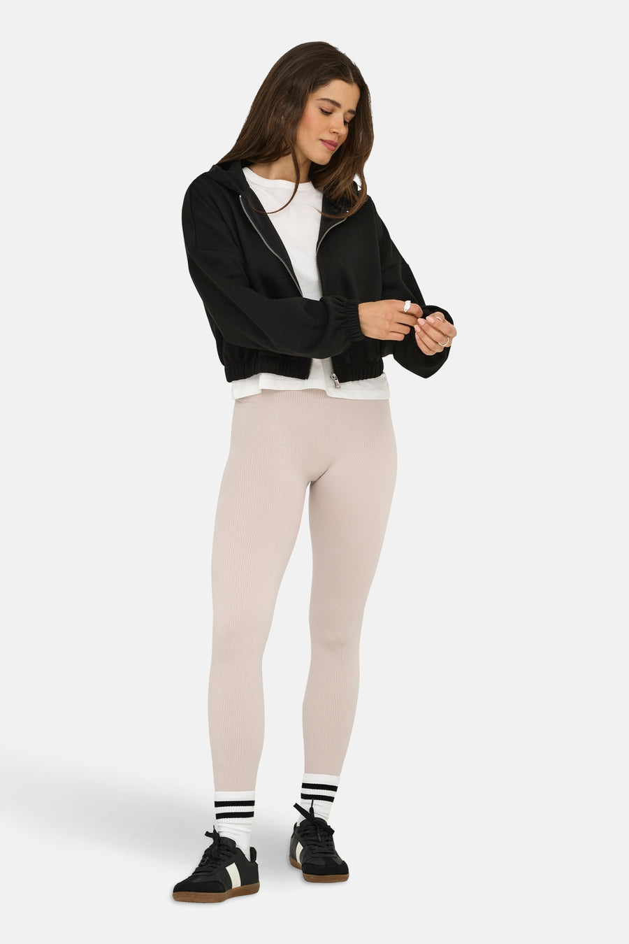 Zwarte bodywarmer van ONLY, gedragen met een wit T-shirt, een beige legging en zwarte sneakers.