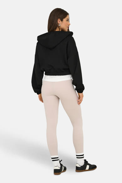 Zwart gilet van ONLY®, gedragen over een wit T-shirt en een beige geribbelde legging.
