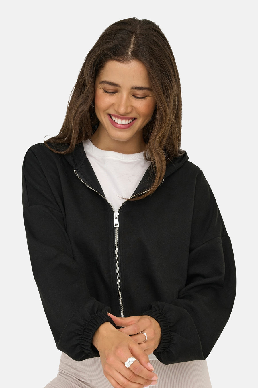 Zwart gewatteerd vest met rits van ONLY, gedragen over een effen wit T-shirt, met een lachende vrouw die naar haar handen kijkt.