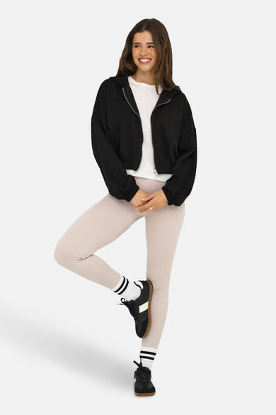 Zwart gilet van ONLY®, gedragen met een wit T-shirt, een beige geribbelde legging, sokken en zwarte schoenen.