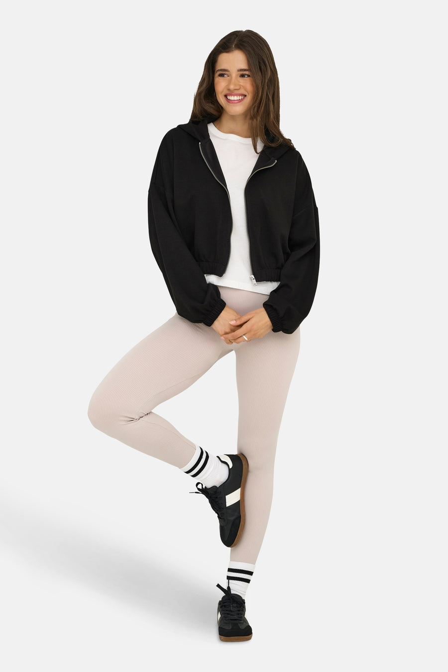 Zwart gilet van ONLY®, gedragen met een wit T-shirt, een beige geribbelde legging, sokken en zwarte schoenen.