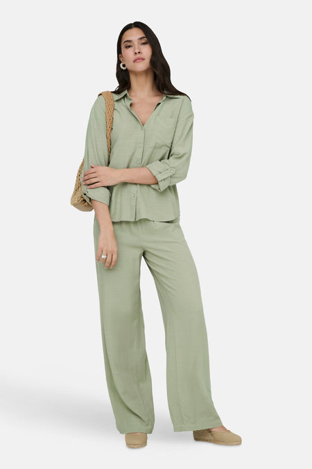 Pantalon vert de JDY, ample avec une texture subtile, porté avec une chemise et un sac assortis.