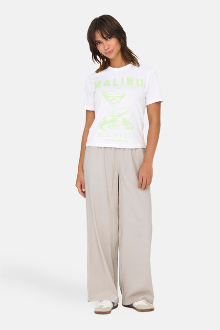 Wit T-shirt met korte mouwen van ONLY®, met Malibu Beach Club-print, gedragen met een beige wijde broek.