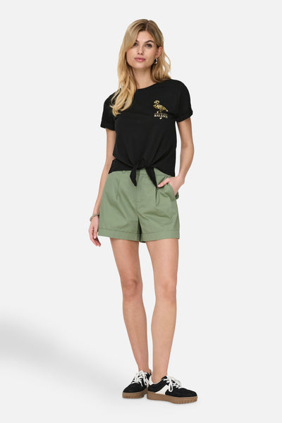 Zwarte korte mouw T-shirt van ONLY®, versierd met een patroon op de borst, gebonden om de taille, gedragen met een groene broek.