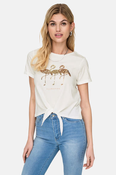 Wit T-shirt met korte mouwen van ONLY®, met glitterende flamingo-print en strik aan de voorkant, gedragen met een spijkerbroek.