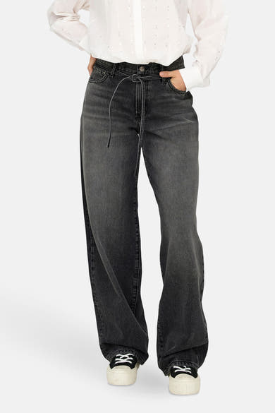Jean droit en denim noir par ONLY, avec cordon de serrage, porté avec une chemise blanche.
