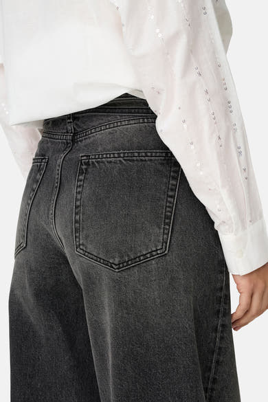Jean droit en denim noir de ONLY, avec une chemise blanche à paillettes discrètes.
