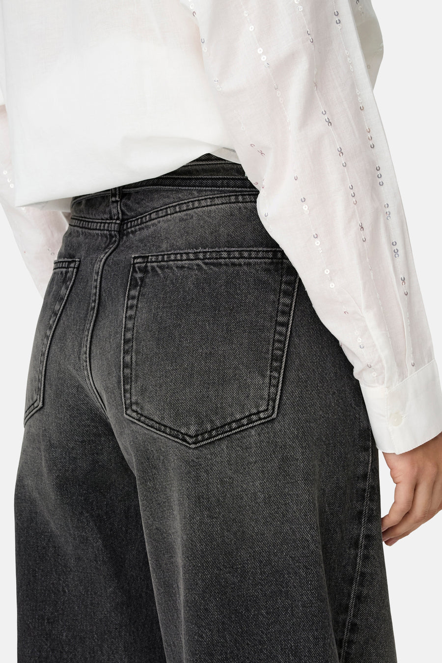 Jean droit en denim noir de ONLY, avec une chemise blanche à paillettes discrètes.
