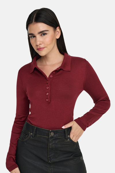 Rode polo met lange mouwen van ONLY, gedragen met een zwarte jeans, met één hand in de zak.
