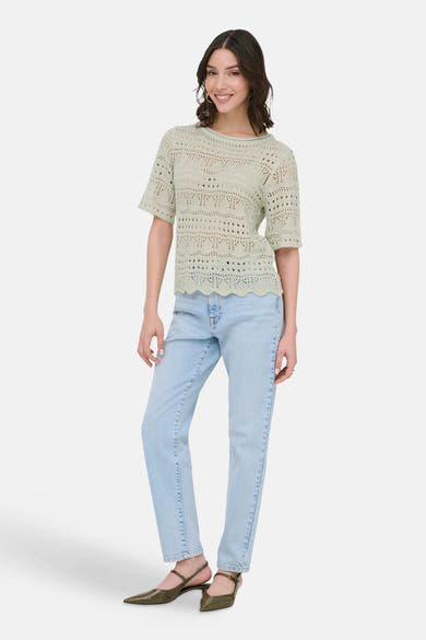 Pull à col rond vert, par JDY, avec motif ajouré, porté avec un jean bleu clair et des escarpins vert olive.