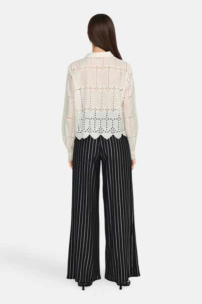 Wit overhemd van JDY, met decoratieve uitsnijdingen, gedragen met een zwart-wit gestreepte broek, achtergezicht.