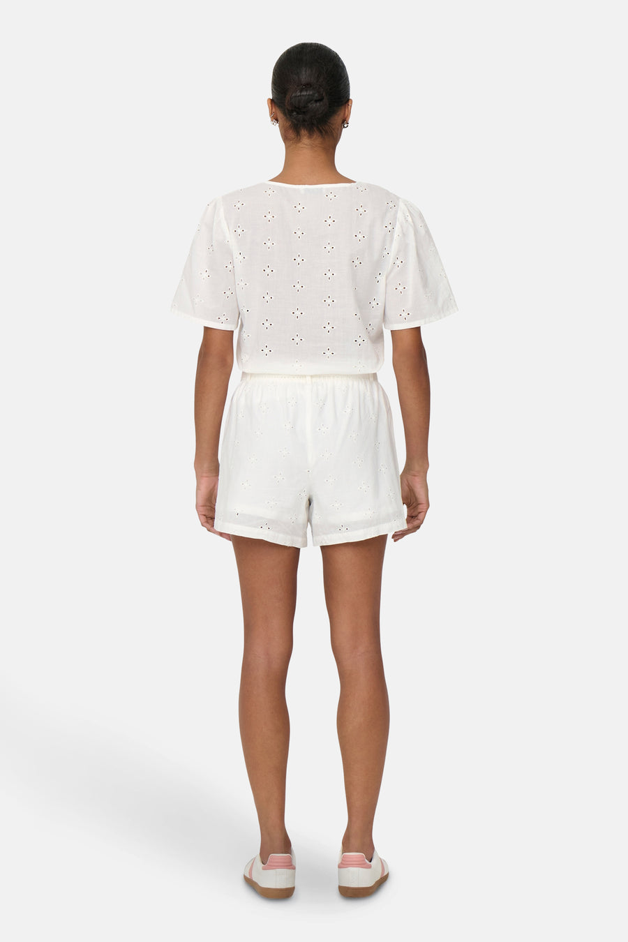 Short blanc de JDY, orné de broderie anglaise et porté avec un chemisier assorti et des chaussures de sport.