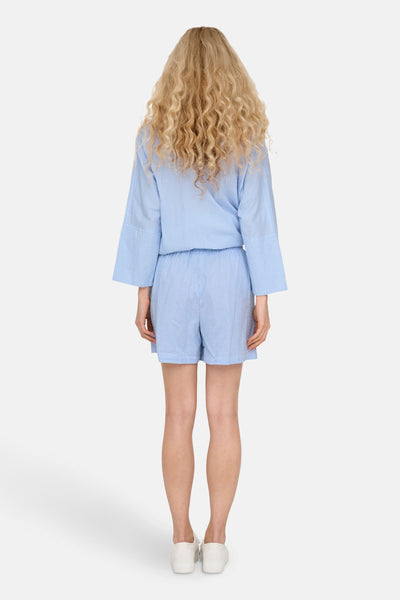 Korte blauwe gestreepte short van ONLY, gedragen met een bijpassend topje, achterzijde.