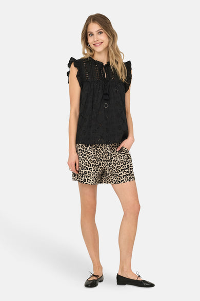 Short beige à motif léopard de ONLY, porté avec un top noir et des ballerines noires.
