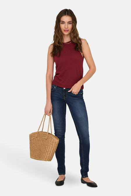 Top bordeaux sans manches de ONLY, porté avec un jean bleu et tenant un panier en osier tressé.