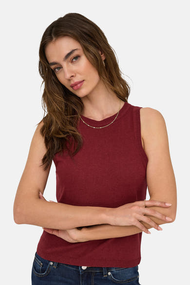 Top sans manches bordeaux de ONLY, porté avec un jean, agrémenté d'un collier et d'une bague dorés.