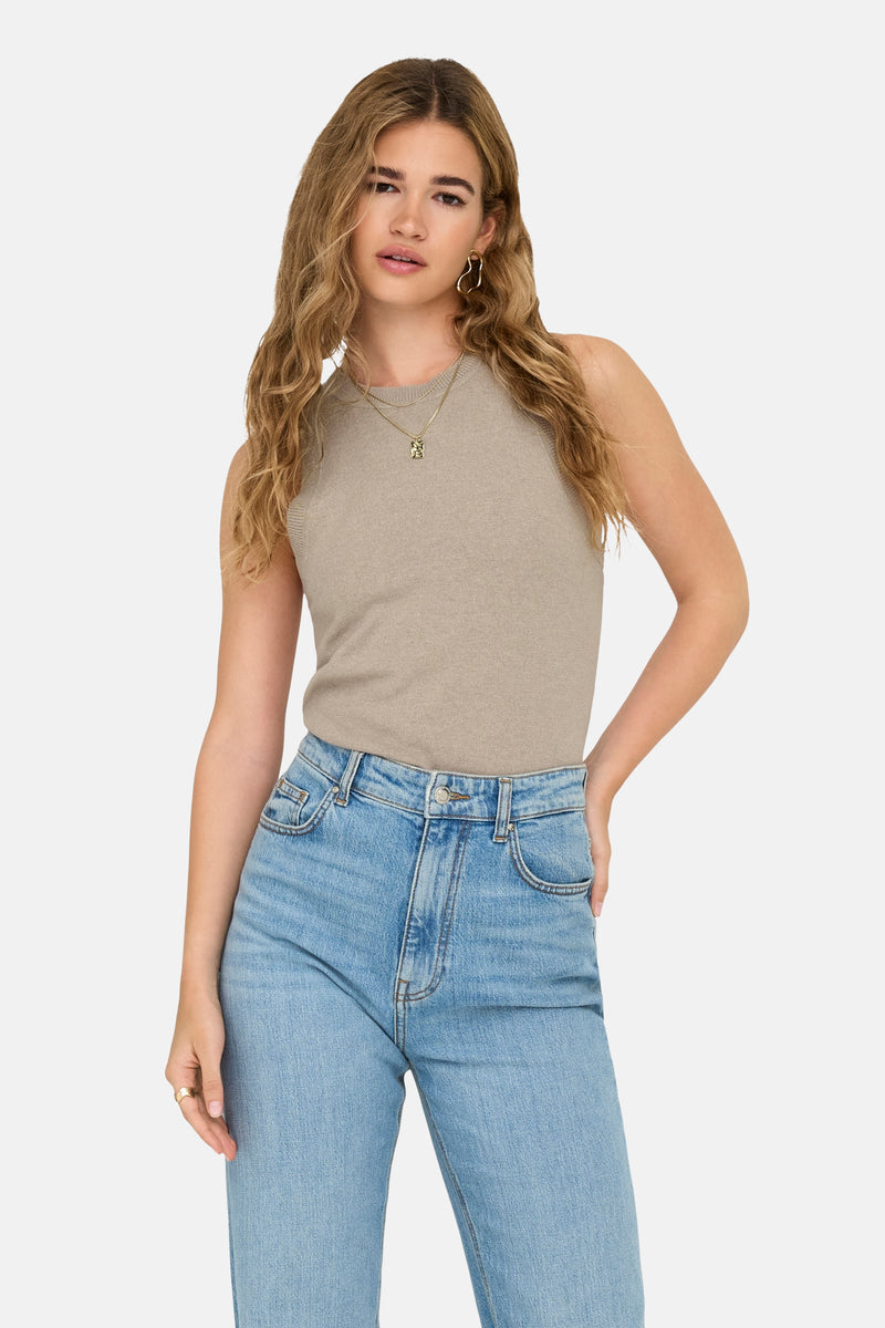 Top sans manches beige par ONLY, porté avec un jean bleu clair, col rond et bijoux dorés.
