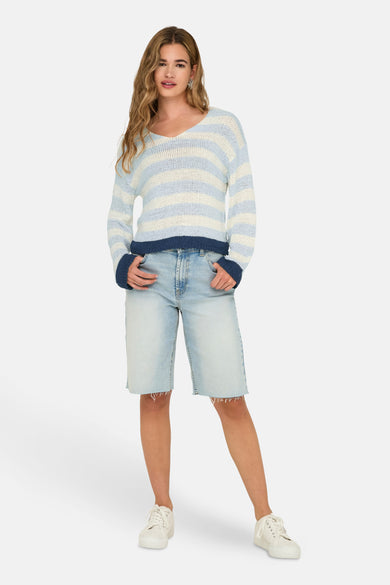 Pull à col en V bleu rayé ONLY, porté avec un short en jean et des baskets blanches.

