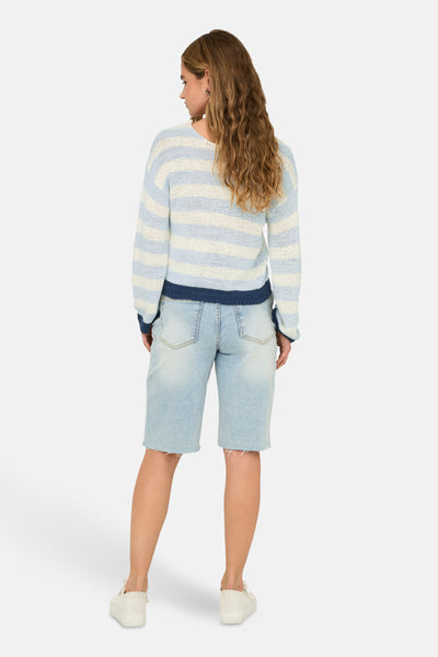 Pull col en V bleu rayé de ONLY, porté avec un short en jean délavé et des chaussures blanches.