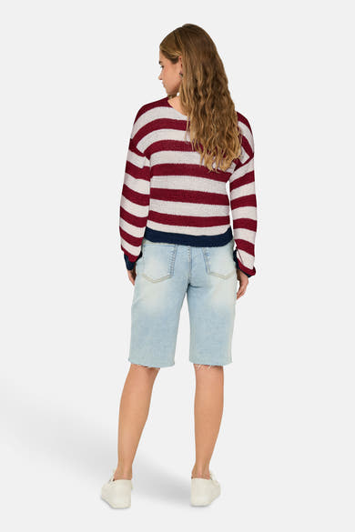 Pull à col en V multicolore de ONLY, rayures horizontales bordeaux et crème, porté avec un short en jean.

