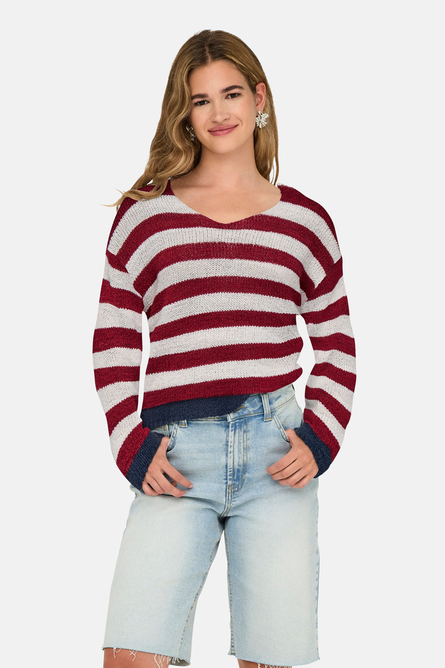Pull à col en V multicolore de ONLY, à rayures horizontales, porté avec un short en jean délavé et des boucles d'oreilles argentées.
