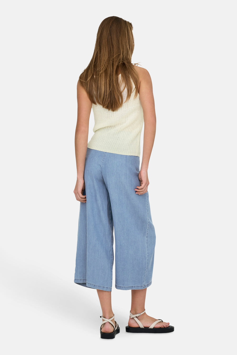 Débardeur beige de ONLY®, porté avec un pantalon large bleu et des sandales à plateforme noires.