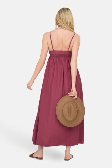 Robe longue rouge by ONLY® avec fines bretelles, tenue par une femme de dos avec un chapeau.