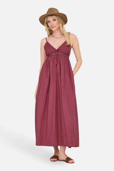 Robe longue rouge de ONLY, avec un haut smocké, et accessoirisée d'un chapeau en feutre marron et de sandales en cuir tressé.