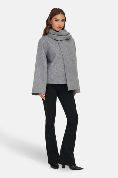 Veste courte grise de ONLY, avec col châle, manches amples et portée avec un pantalon noir évasé.
