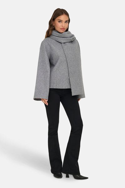 Veste courte grise de ONLY, avec col châle, manches amples et portée avec un pantalon noir évasé.
