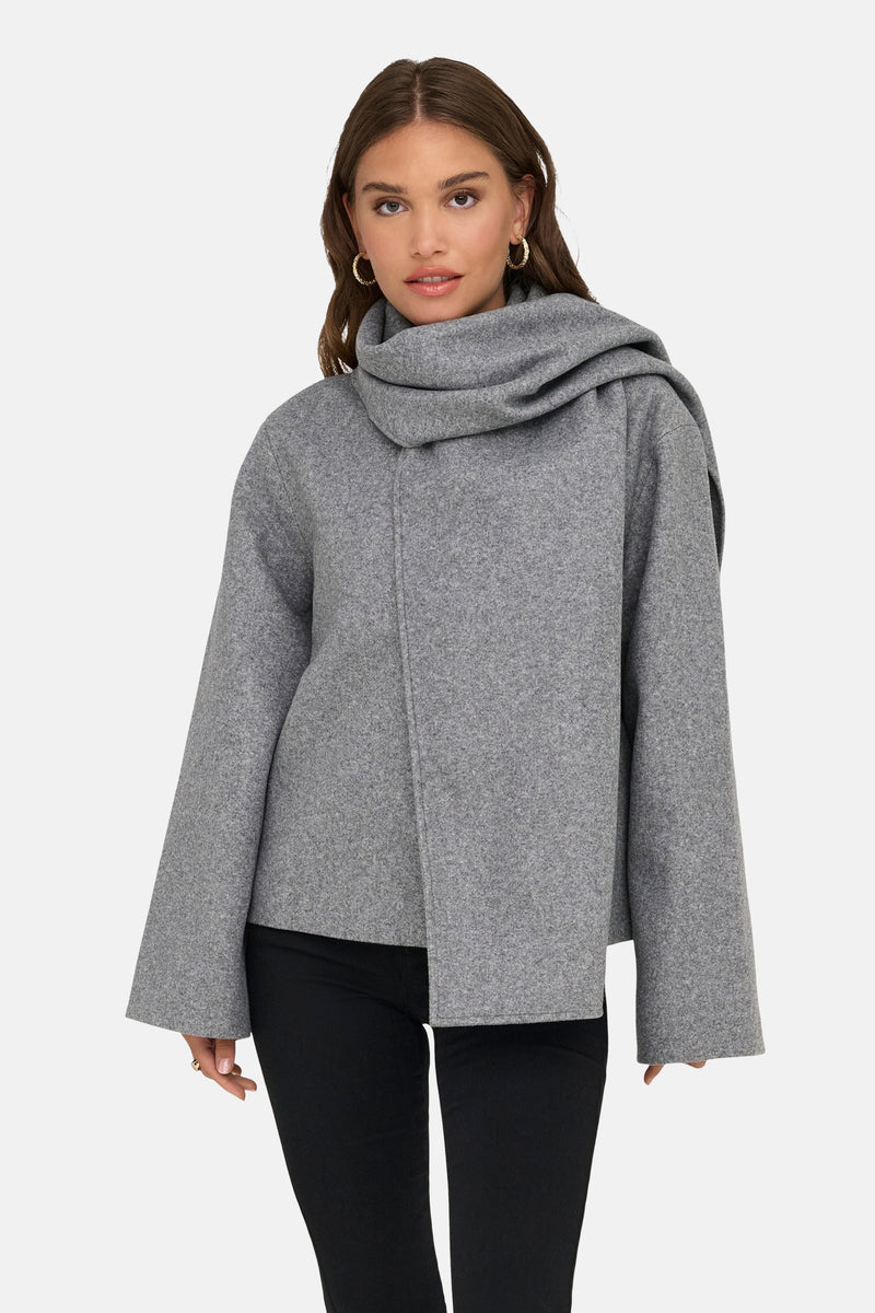 Veste courte grise ONLY®, avec large col châle, portée avec un pantalon noir.
