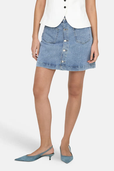 Jupe en jean bleu clair courte de ONLY®, boutonnée sur le devant avec poches plaquées, portée avec des chaussures à talons bleu jean.