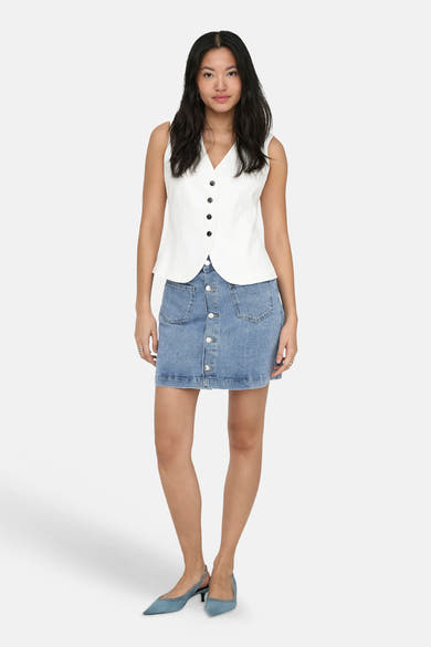 Jupe mini en jean bleu clair de ONLY® avec boutonnage frontal et poches, portée avec un gilet blanc.