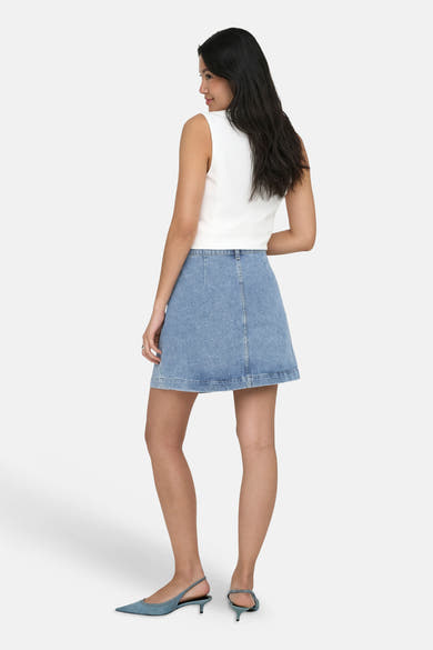 Jupe courte en jean bleu clair de ONLY®, vue de dos, portée avec un haut blanc et des talons bleus.