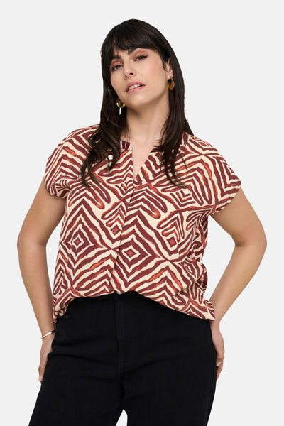 Multikleurig mouwloos overhemd van CARMAKOMA met rode en beige zebra-geometrische print, gedragen met een zwarte jeans.