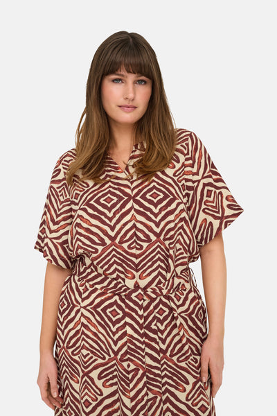 Multikleurige jurk van CARMAKOMA met een geometrisch zebrapatroon en een strikceintuur.