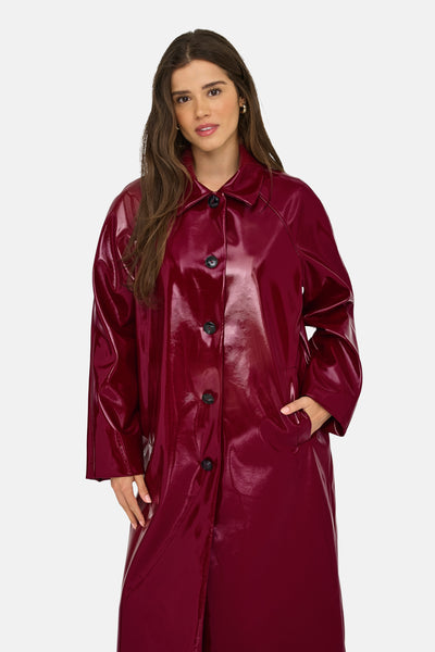Lange bordeaux glanzende jas van ONLY, met zwarte knopen en een hand in de zak.