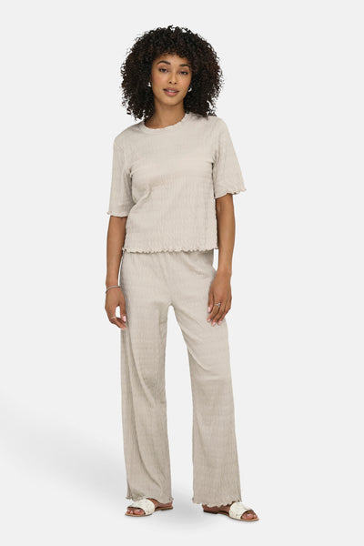 Beige T-shirt met korte mouwen van ONLY, met een bijpassende textuur broek en witte sandalen.