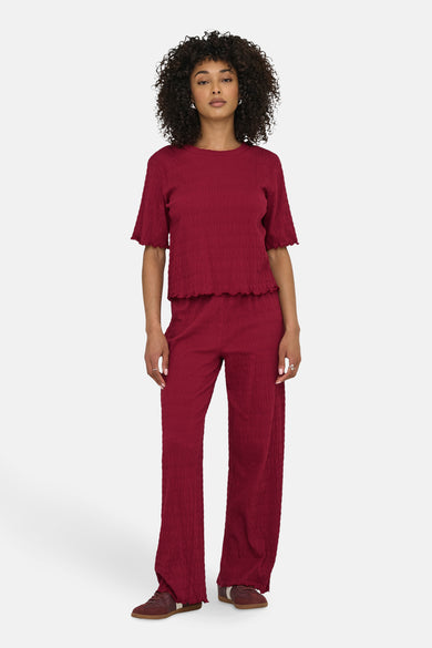T-shirt rouge à manches courtes de ONLY, en tissu gaufré, porté avec un pantalon coordonné.