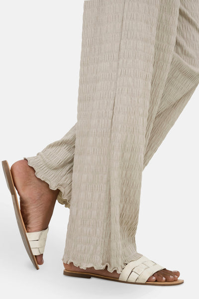 Pantalon beige froncé van ONLY®, porté avec des sandales blanches, bas de pantalon à volants.