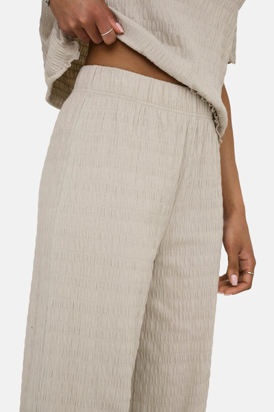 Pantalon beige texturé de ONLY®, avec une taille élastique et un anneau à la main.