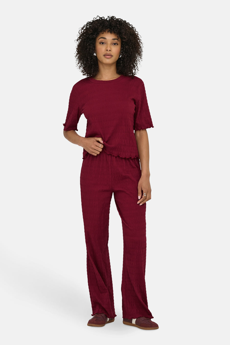 Bordeaux broek van ONLY, met een geplooide textuur en uitlopende pasvorm, gedragen met een bijpassend topje en bruine schoenen.